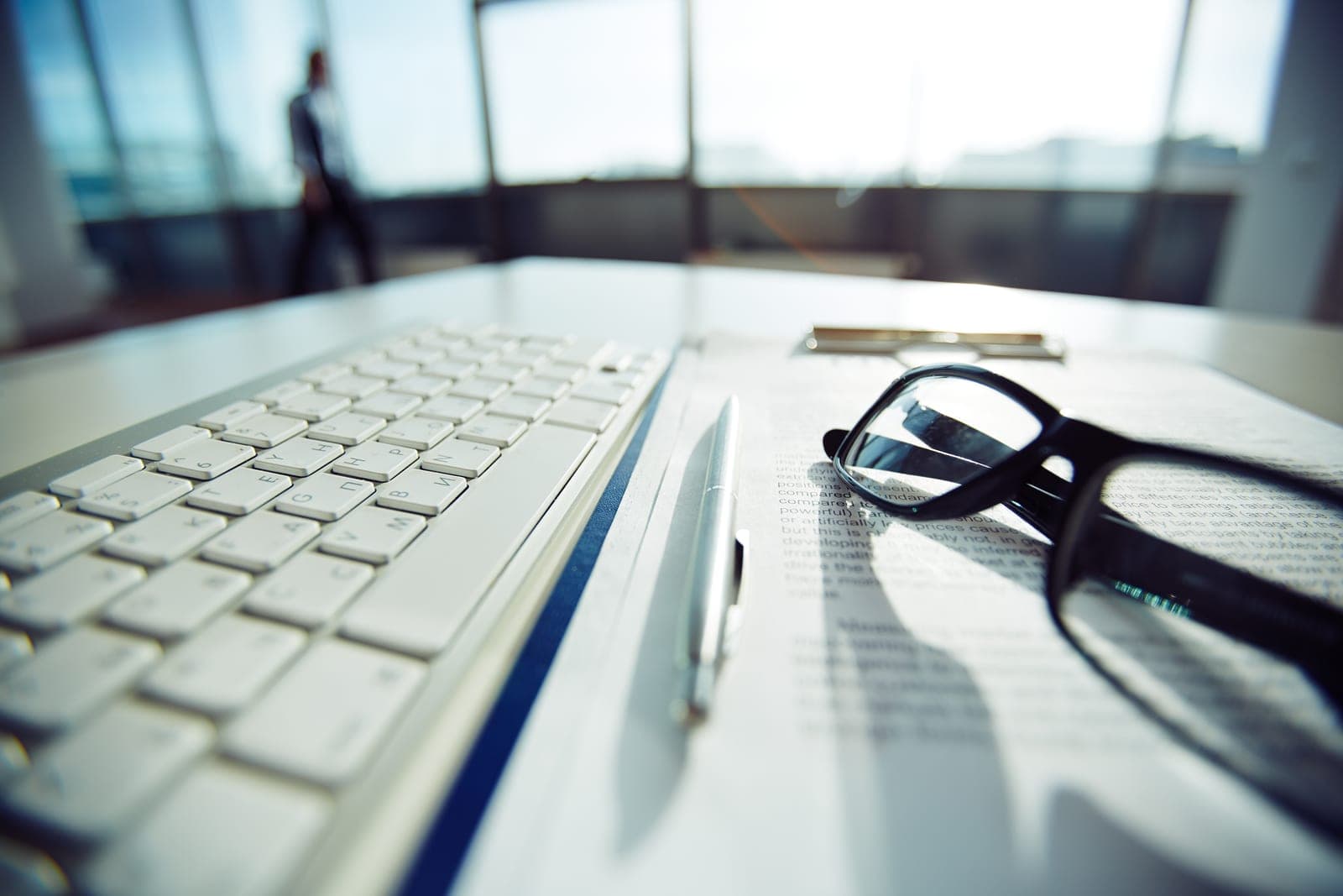 Glasses resting on a keyboard next to a terms document